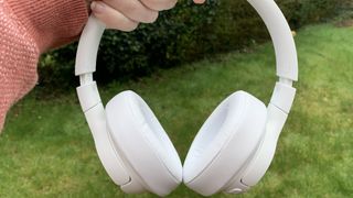 The jbl tune 750btnc over-ear wireless headphones in white pictured against a grassy background.