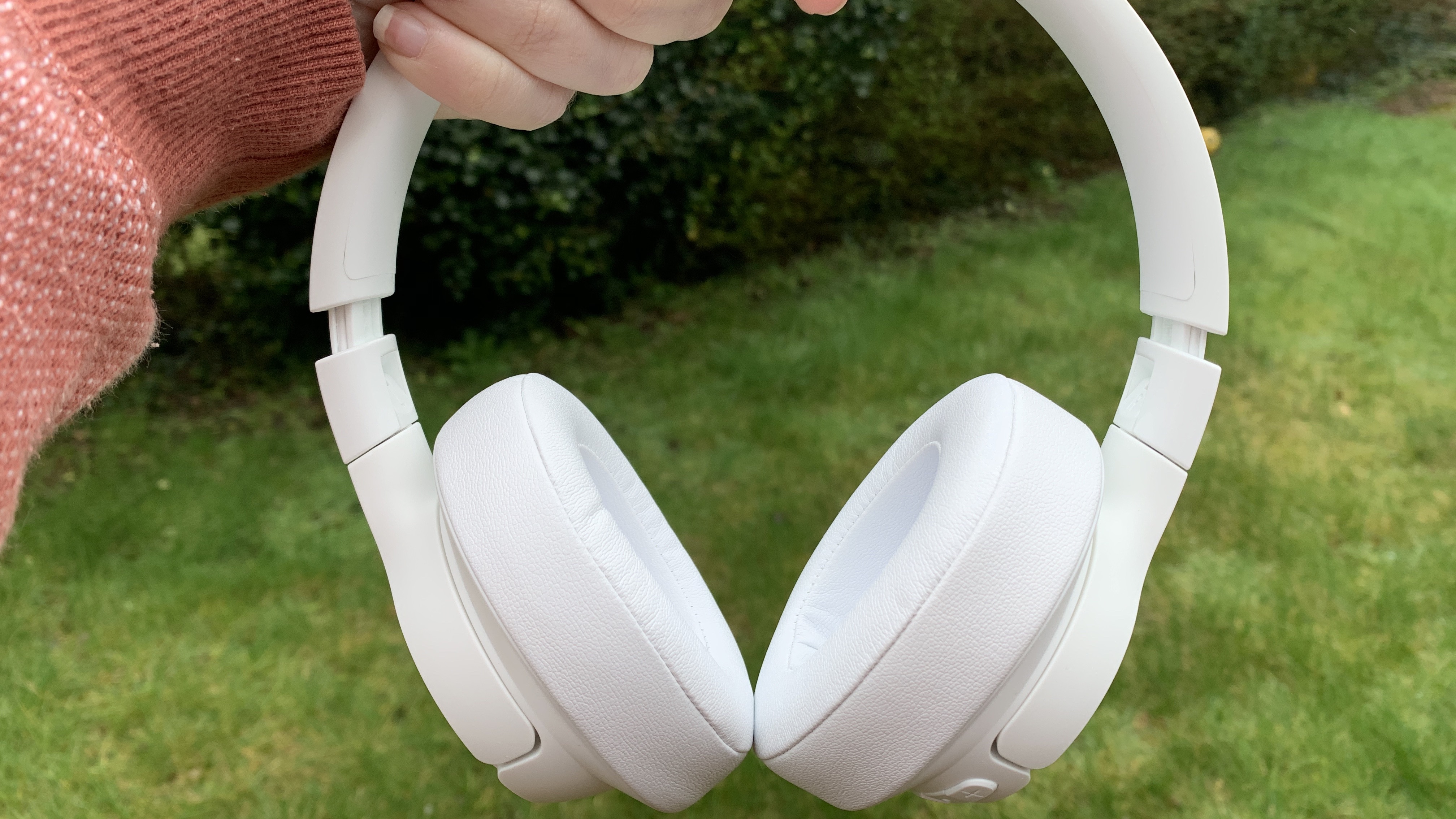 Tampilan dekat headphone on-ear jbl tune 750btnc berwarna putih dengan latar belakang rumput