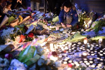 A child looks at tributes left at the site of one of the terrorist attacks on Paris in 2015.