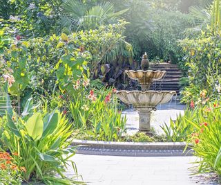 A beautiful ornate two-tiered water feature - fountain with tropical planting