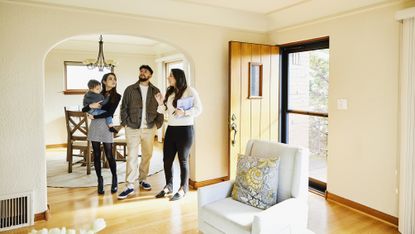 A couple with a small child look at a home for sale with a real estate agent.