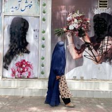 A woman in Afghanistan walks past a closed beauty salon