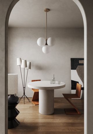 A dining area with a white round table, white globe pendants, and a floor lamp with white shades