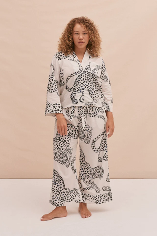 woman wearing a boxy button up shirt and trouser pyjama sets with leopards printed all over