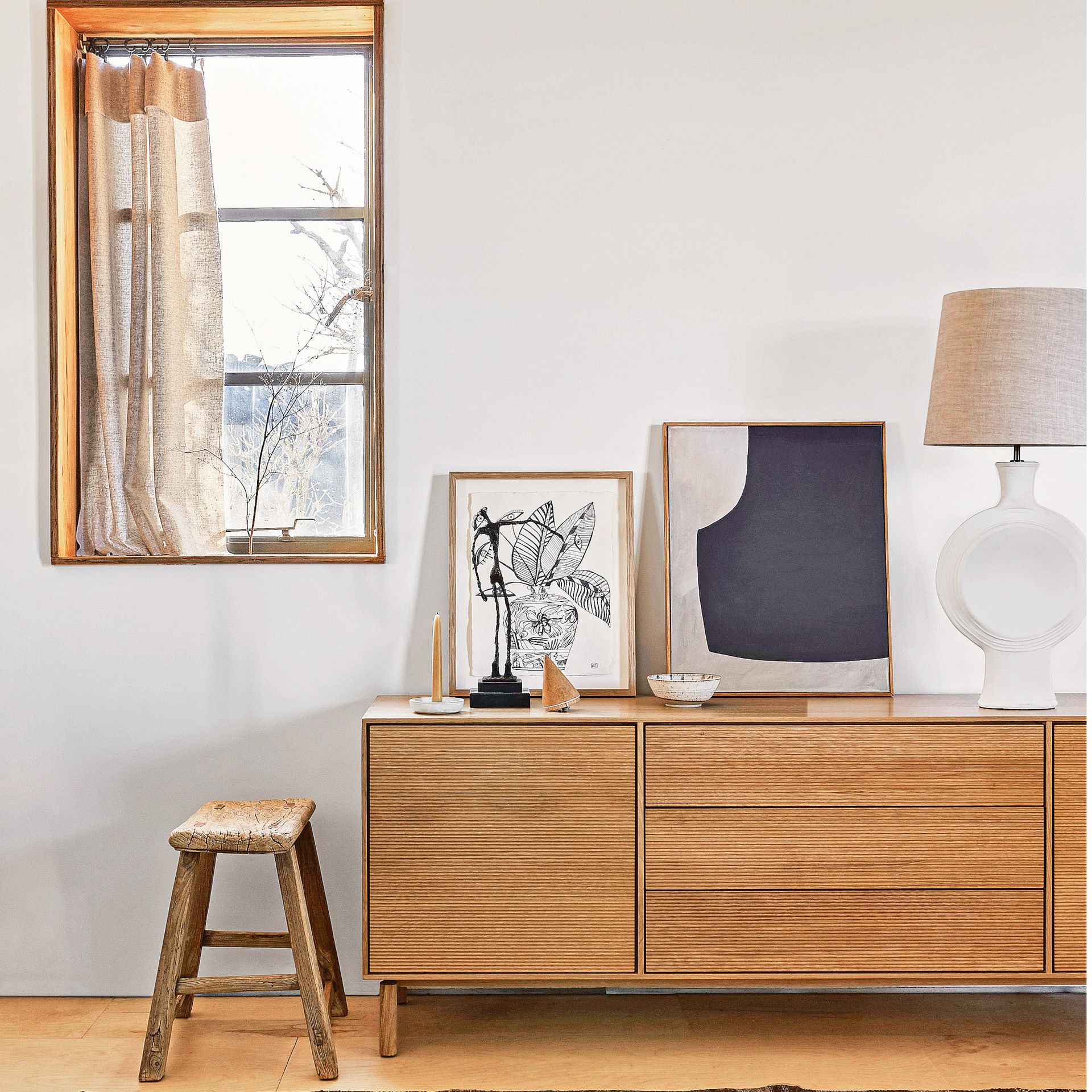 living room with wooden cabinet, wooden flooring, wooden stool, beige lamp and large mirror