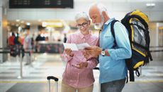 A senior couple examines their boarding passes while at the airport.