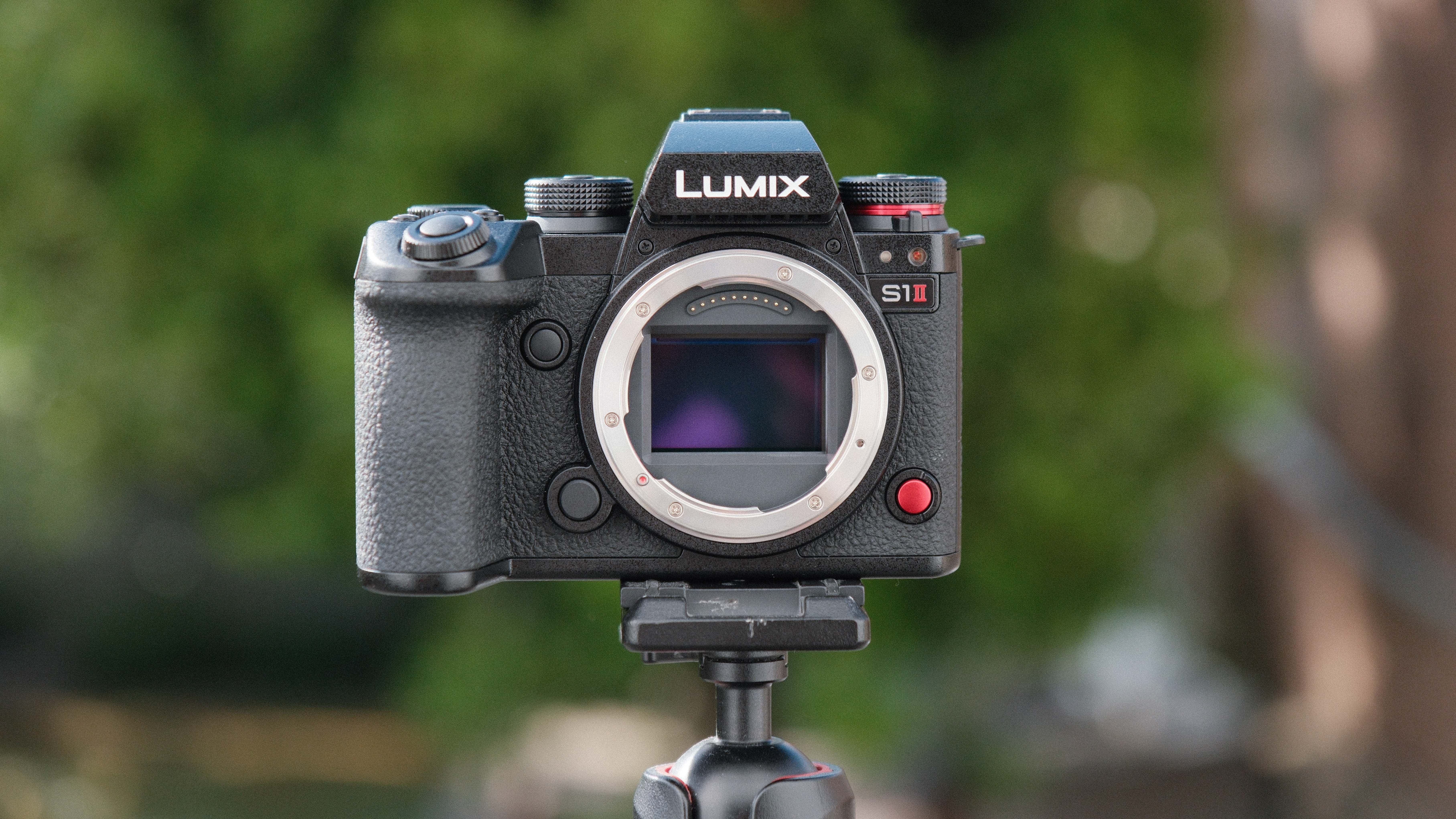Panasonic Lumix S1 II camera on a tripod with green trees in the background