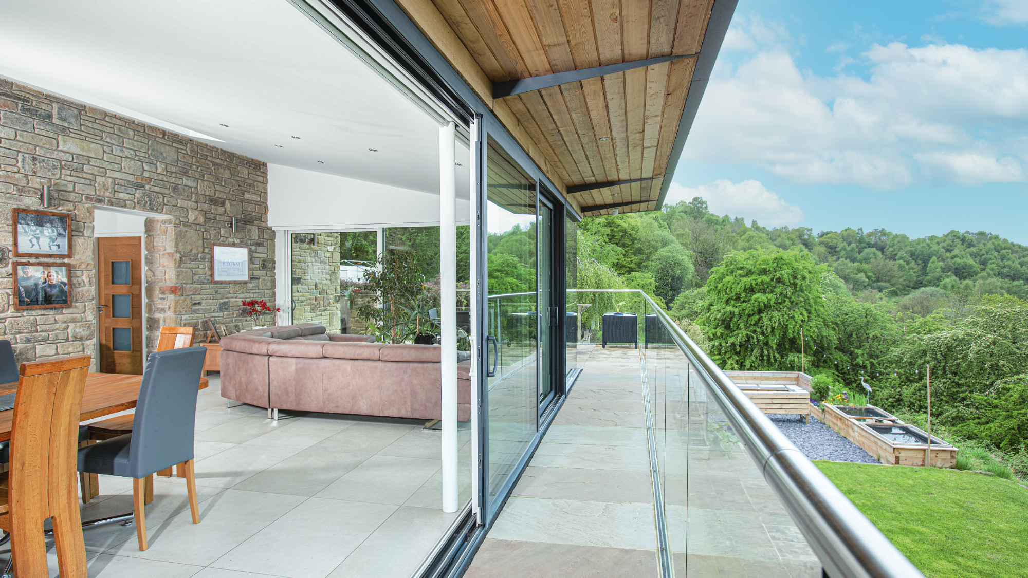 view along balcony of modern self build with large sliding patio doors leading into living and dining area