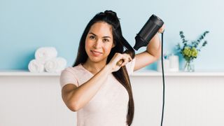 The Shark Style iQ hair dryer being used by a womann to blow dry her hair straight