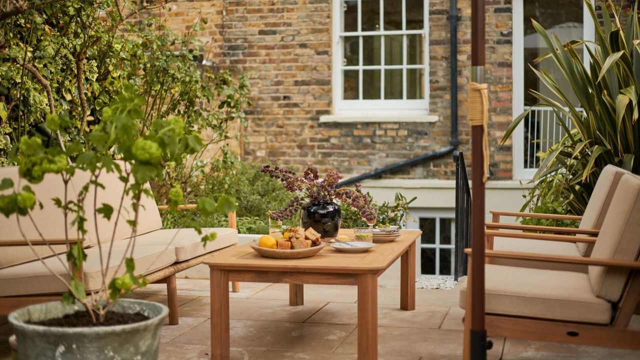 The Anna Barnett Kew patio furniture collection on a stone patio behind a brick house