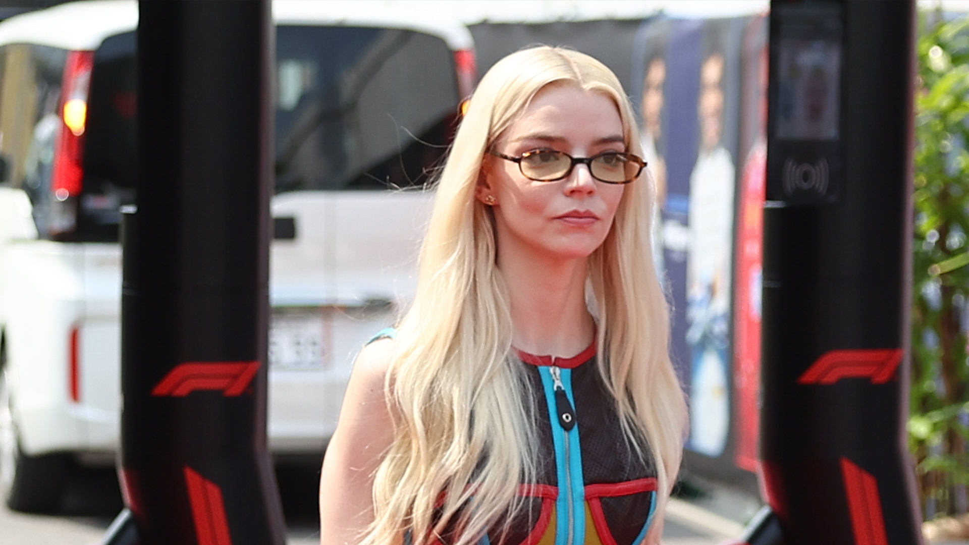 Anya Taylor-Joy wearing a multicolor top, black pants, and red sandals.