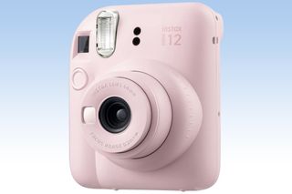 An image of a pink Fujifilm Instax Mini 12 on a blue and white background