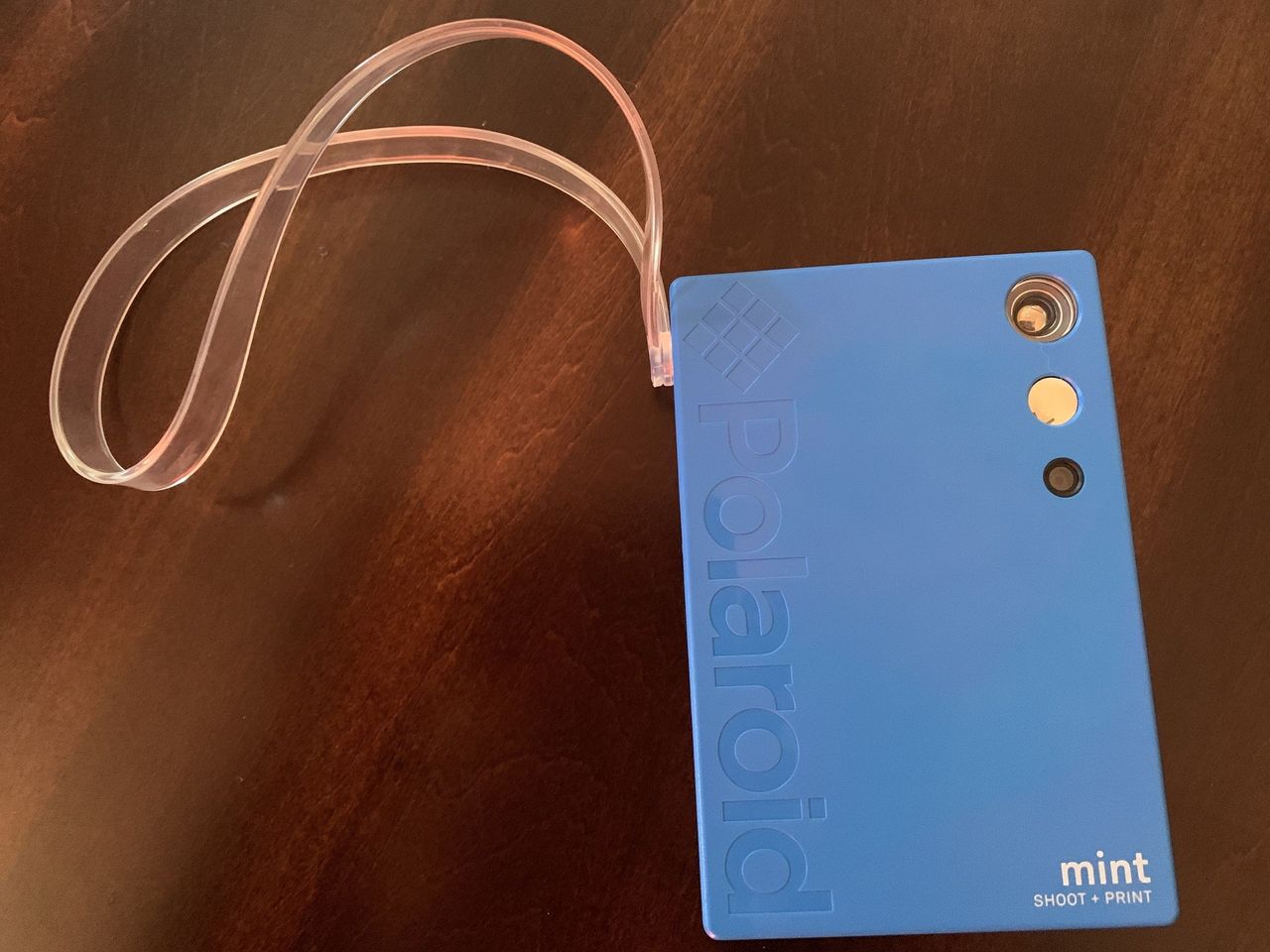 Blue Polaroid Mint Camera &amp; Printer laying on wooden table