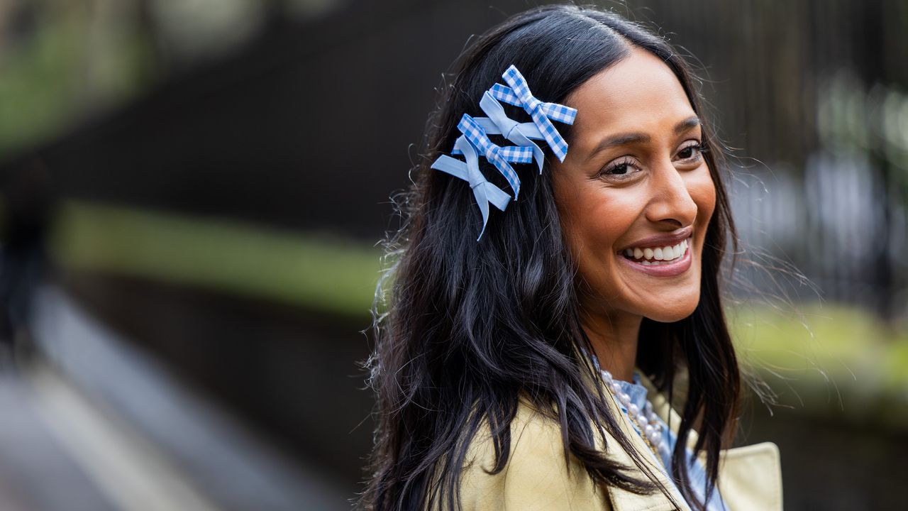 Zeena Shah wearing blue bows in hair with shiny brunette waves thanks to the best hair oils