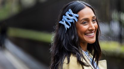 Zeena Shah wearing blue bows in hair with shiny brunette waves thanks to the best hair oils