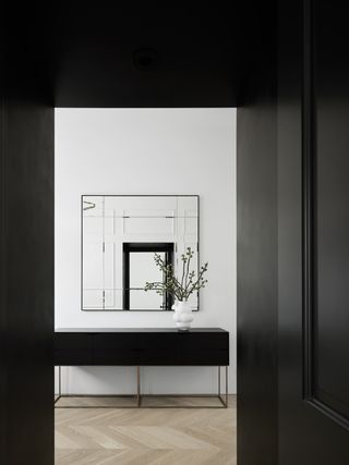 An entryway with black doors and white walls