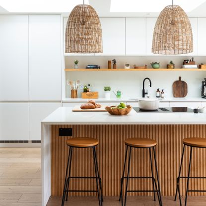 Scandi-style white kitchen with breakfast bar and large oversized pendants