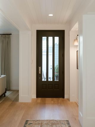 A minimalist entryway with black door and wood floors