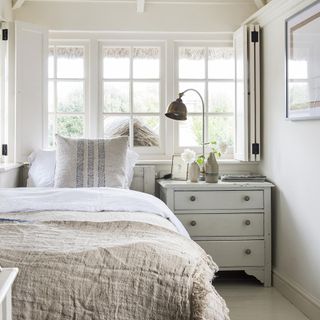 White bedroom with open shutters and neutral bedlinen