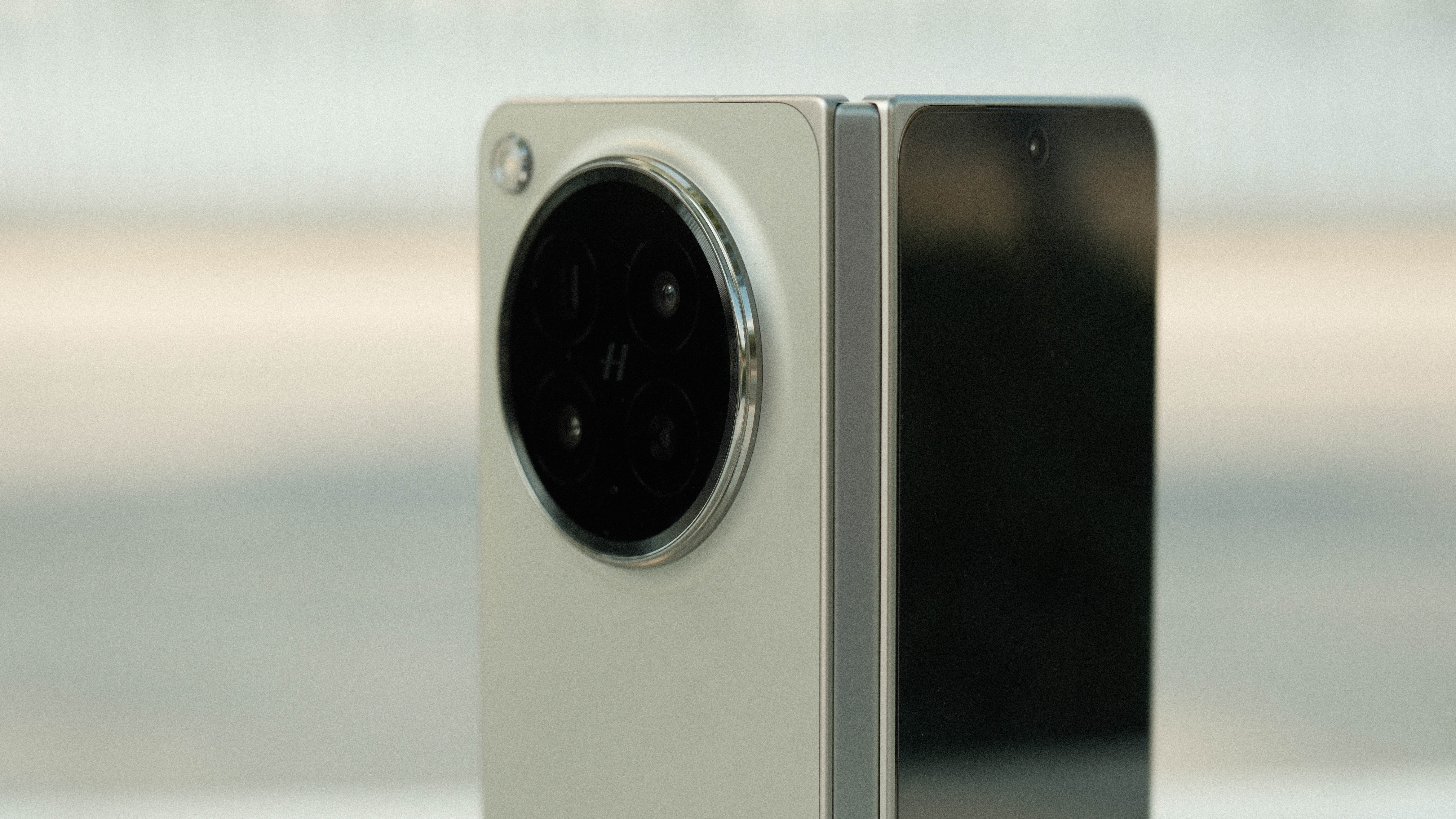 A side-profile view of the phone partially folded, highlighting the hinge mechanism and the thickness of the two halves. The large camera bump is visible on the rear panel.