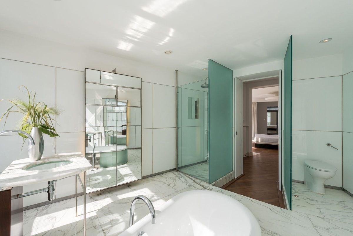 The en suite bathroom is white with glass panelled shower with a small archway to the bedroom