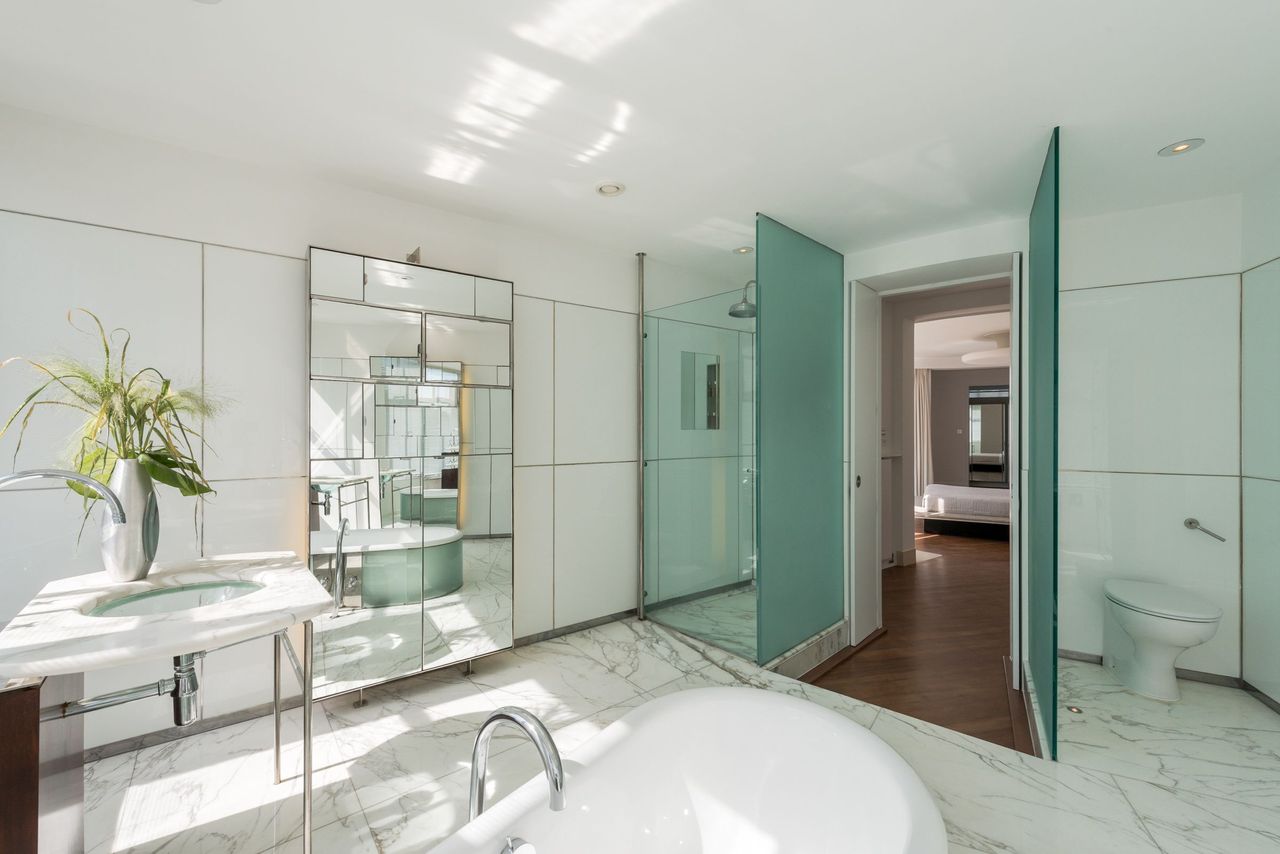 The en suite bathroom is white with glass panelled shower with a small archway to the bedroom