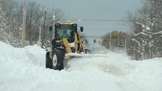 A National Guard loader clears a road after an intense lake-effect snowstorm