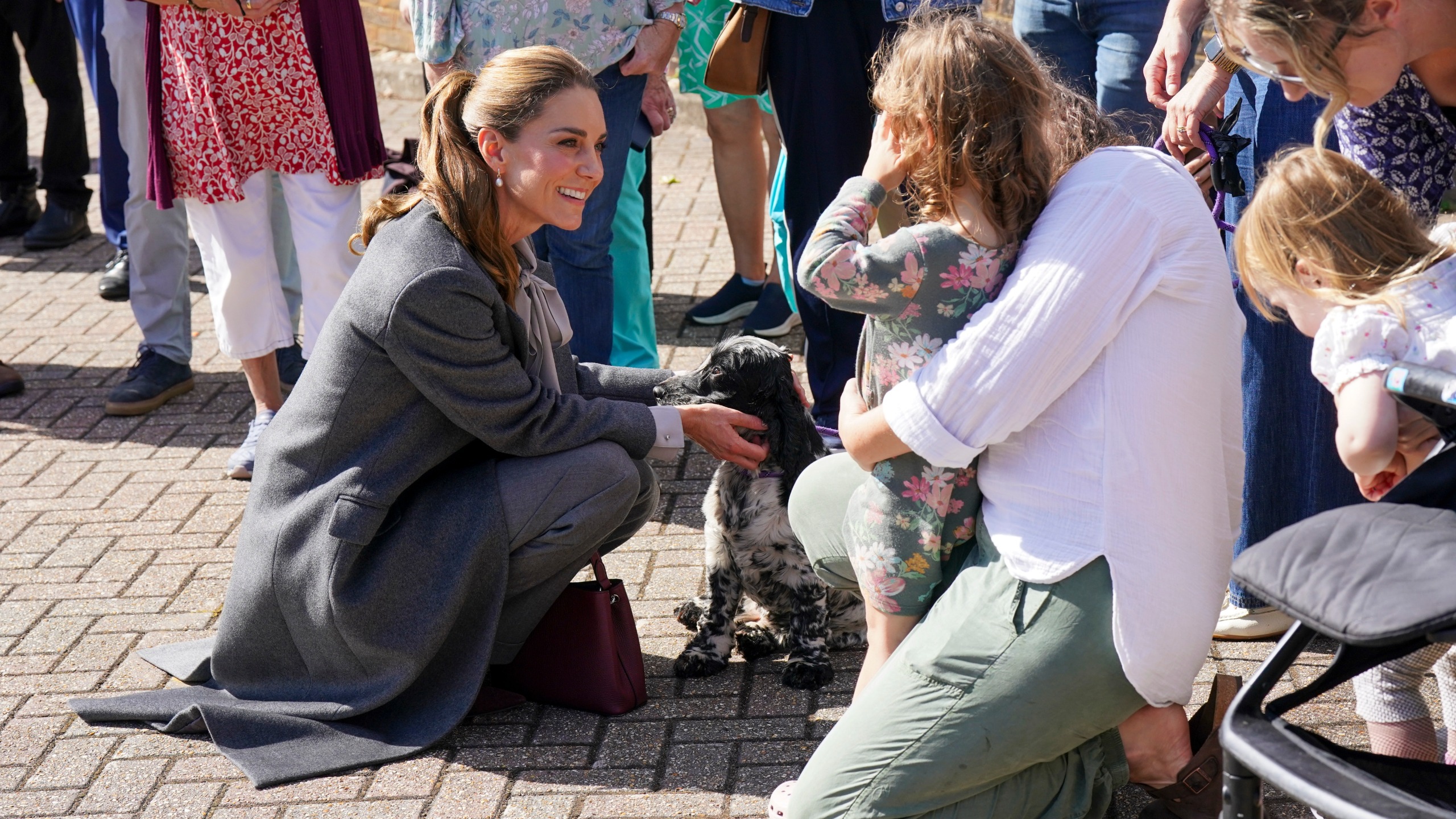 Catherine, Princess of Wales bends down and strokes a dog during her visit to West Sussex