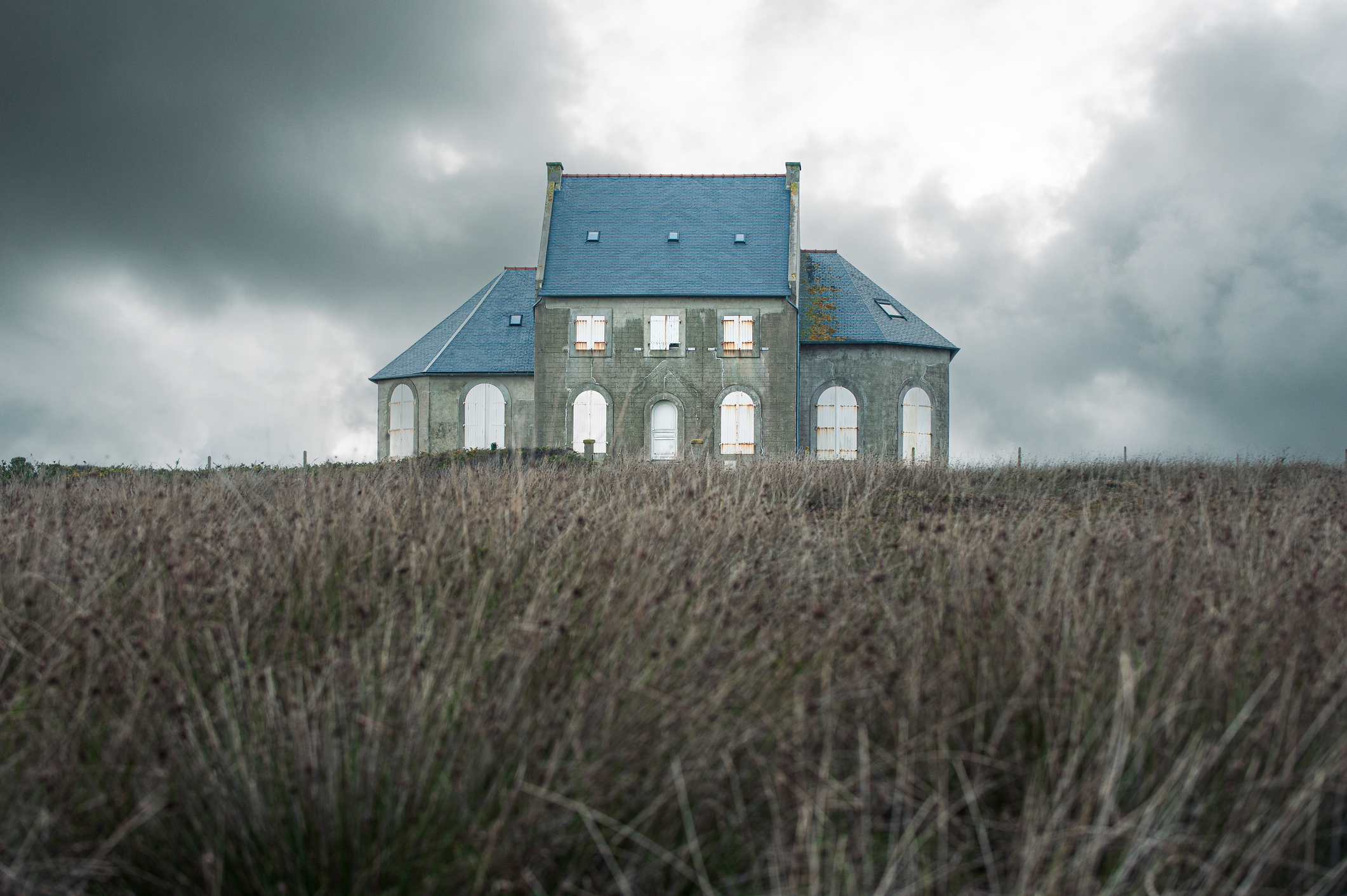 Abandoned house with closed shutters under a moody sky