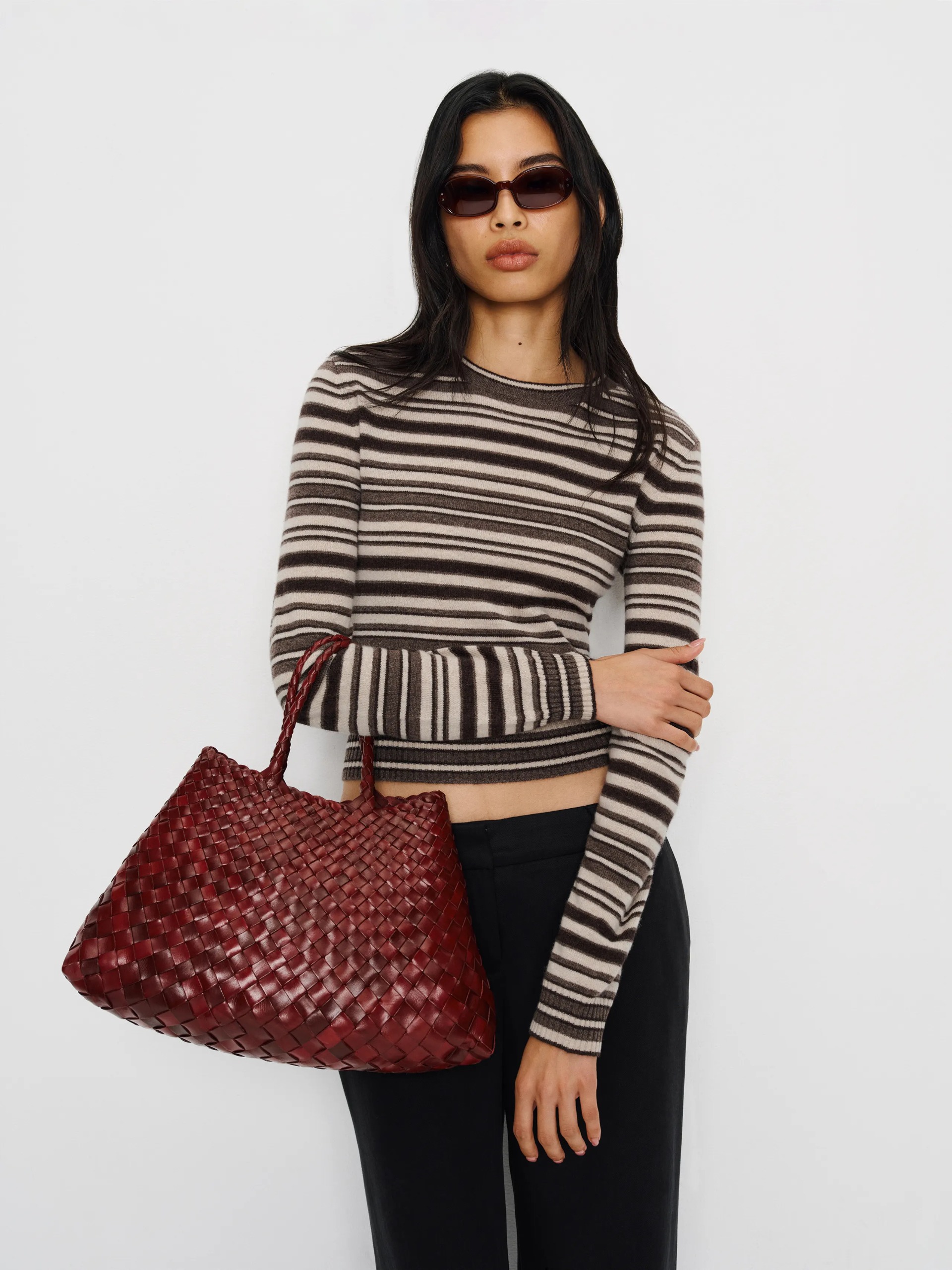 A model wearing a thin striped sweater from Reformation