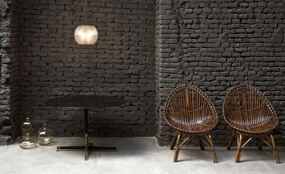Wooden chairs with dark painted brick wall behind