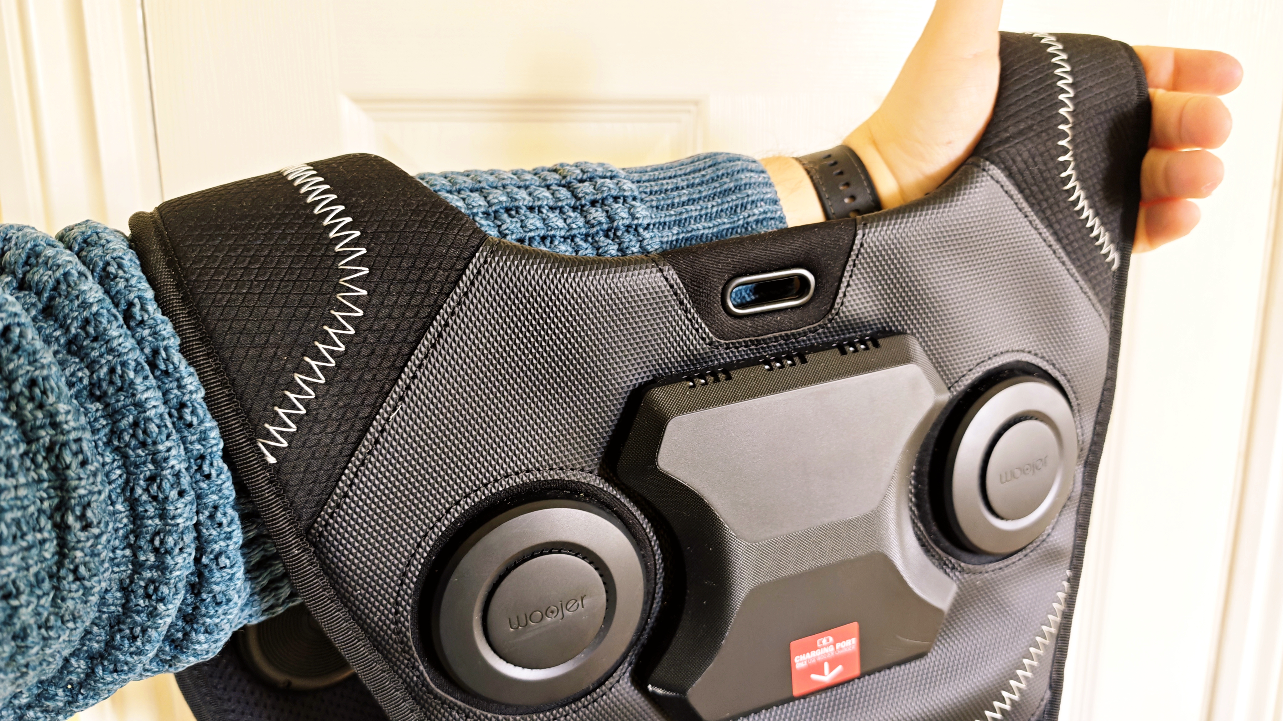 A black Woojer Vest 4 on a wooden floor