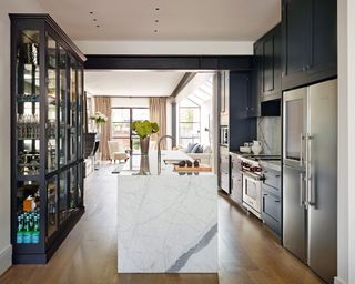 A sleek open plan kitchen with marble island and midnight blue cabinetry.