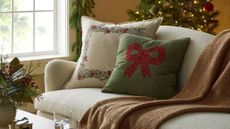 Festive throw pillows and blankets styled in a cozy Christmas living room