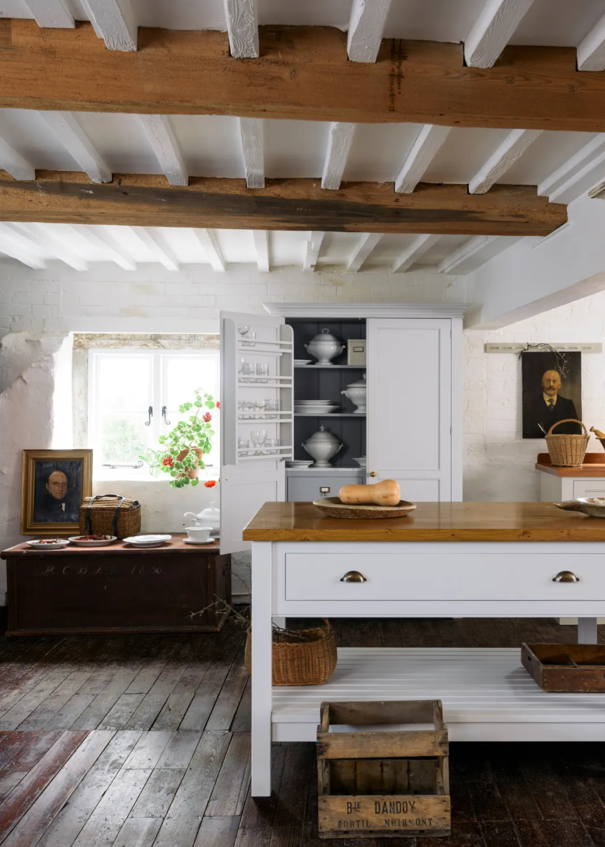 a rustic country kitchen with wooden beams, white cabinetry, and wooden surfaces