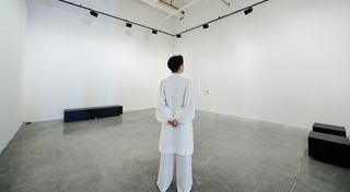 Phạm Minh Hiếu stands and looks at his all-white art space brought to light with d&b Soundscape.