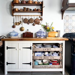 freestanding cabinet with wooden worktop and vegetable trays open shelving with copper pans