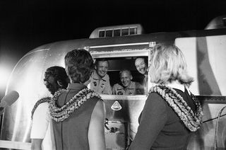 Apollo 11 astronauts, still in their quarantine van, are greeted by their wives upon arrival at Ellington Air Force Base on July 27, 1969.