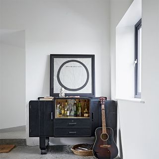 room with white wall and mini bar with guitar