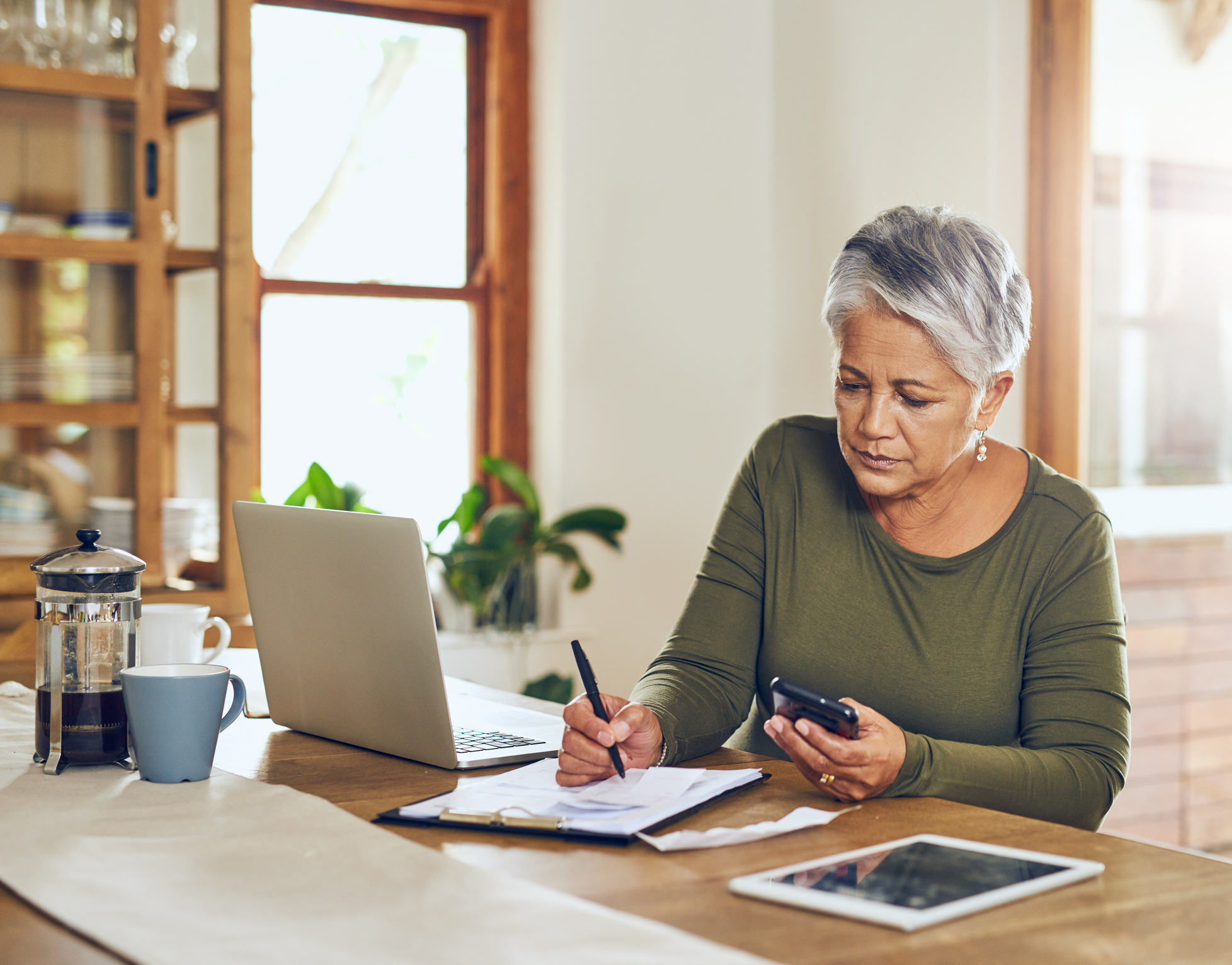 A middle-aged woman reviewing her finances at her dining table.