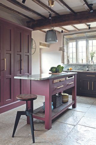 A plum coloured kitchen with matching movable island