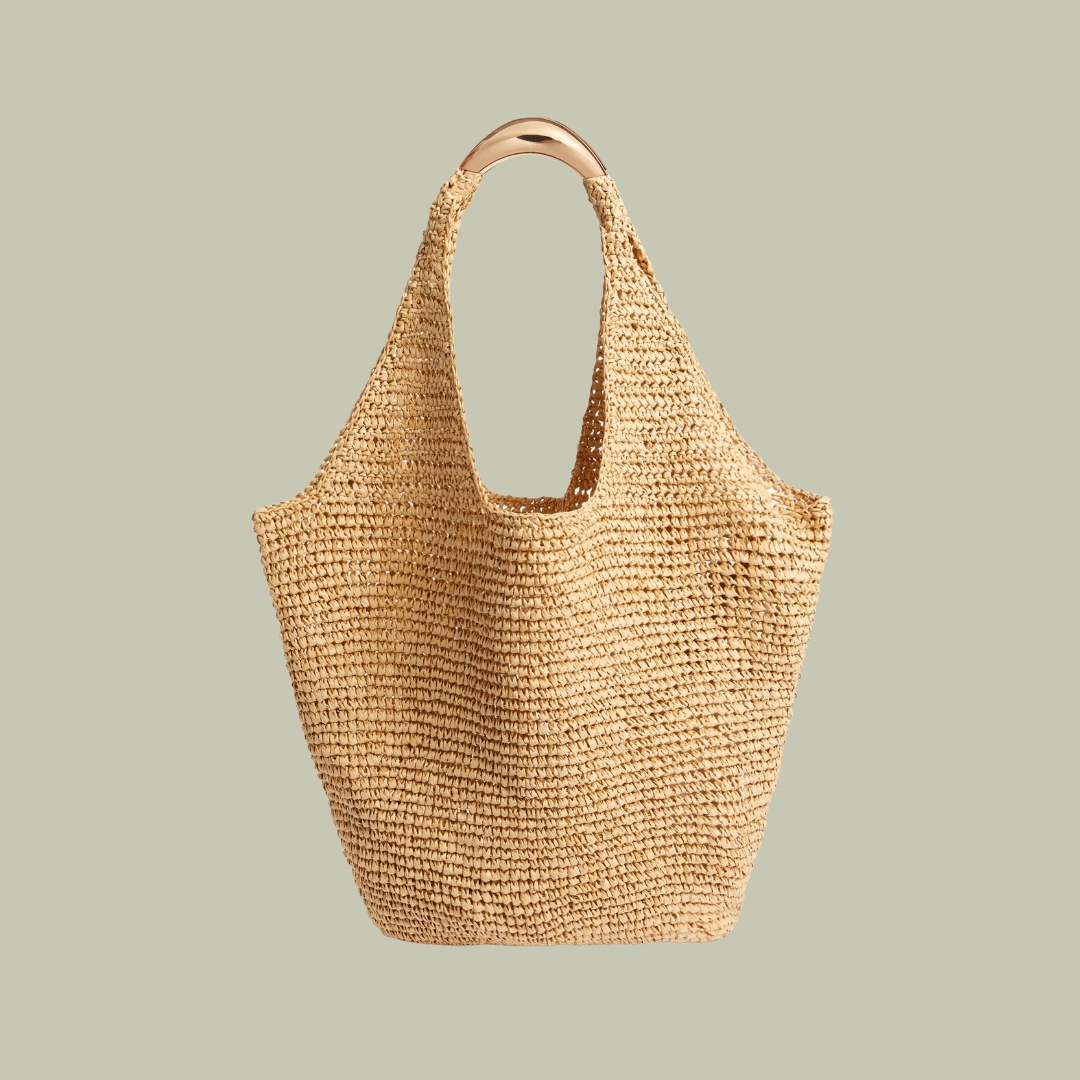 M&S Collection Straw Tote Bag with brass-plated handle against a pale green background.