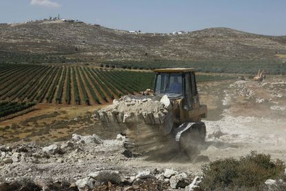 A bulldozer clears land in the West Bank.