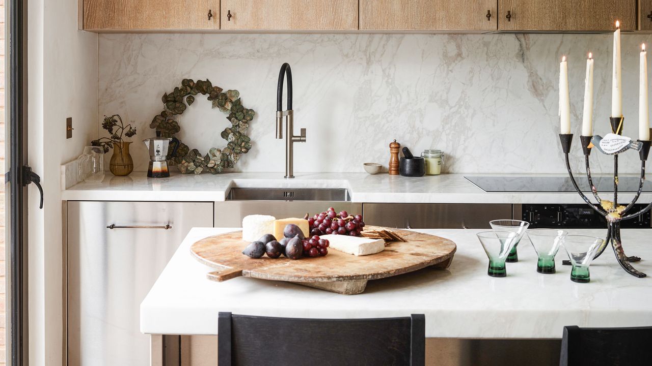 a kitchen island with hosting essentials such as four glasses, a candelabra and a large wooden cheeseboard