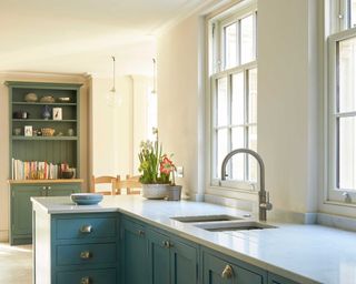 blue kitchen with steel tap and white worktops