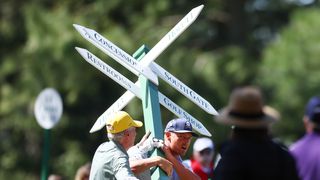 Bryson DeChambeau carries a sign away at The Masters