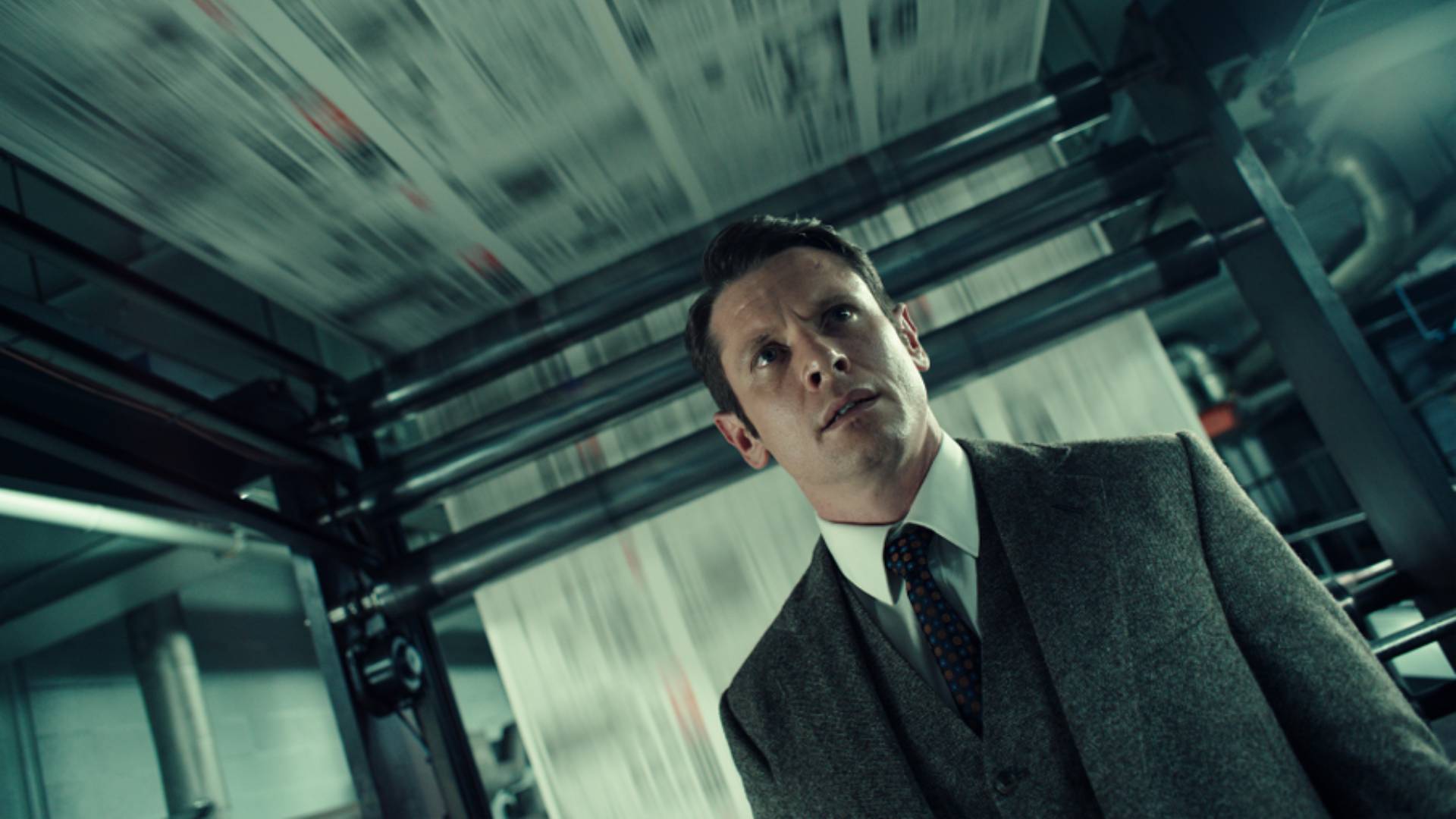Jack O'Connell as The Sun newspaper editor Larry Lamb in Ink, standing in front of a printing press