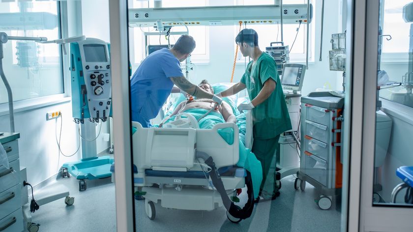 two healthcare providers place defibrillator paddles on a patient&#039;s chest in an intensive care unit