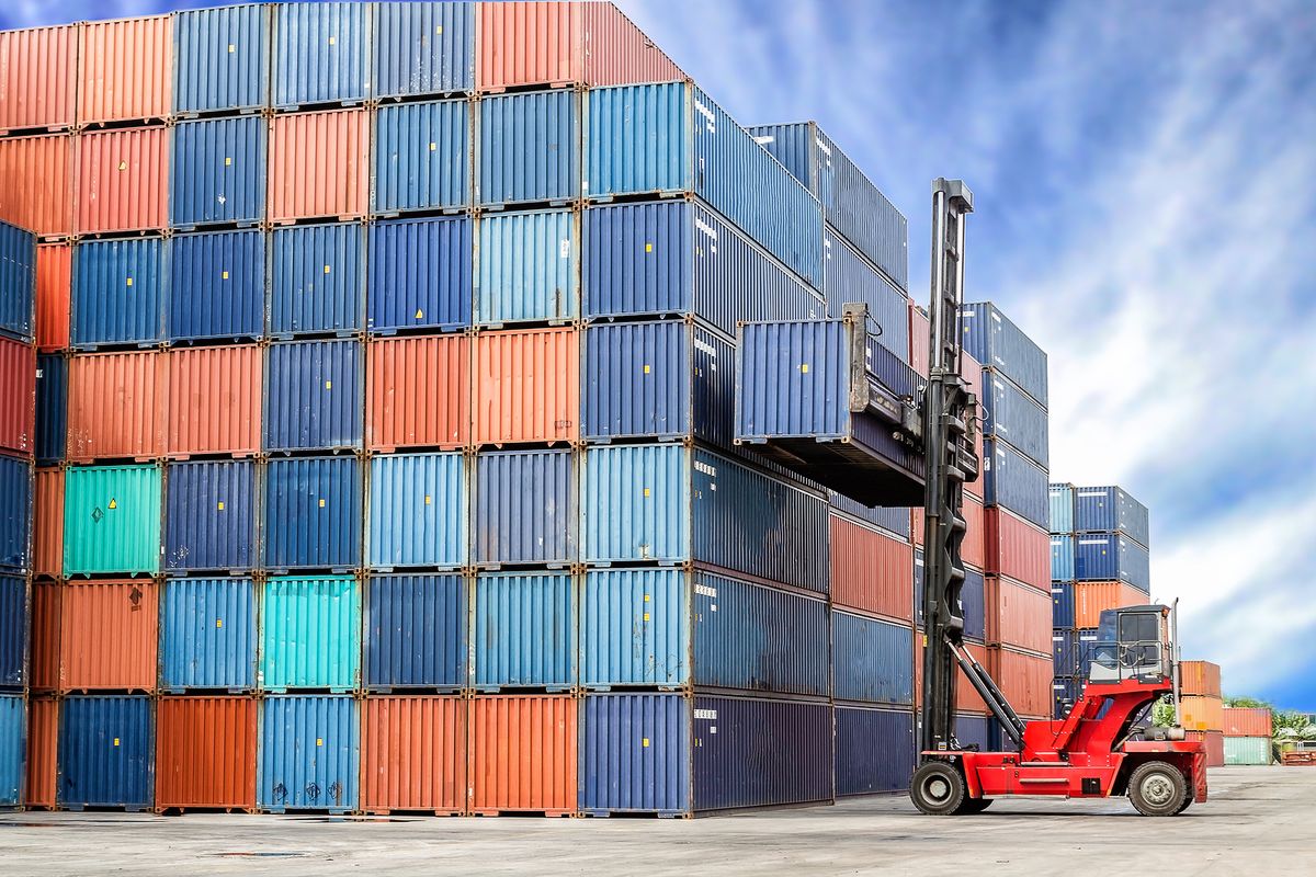 A stack of colourful containers being built up by a forklift truck