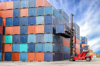 A stack of colourful containers being built up by a forklift truck